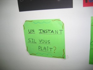 cartel Un instant, s'il vous plaît.... (un momento por favor)